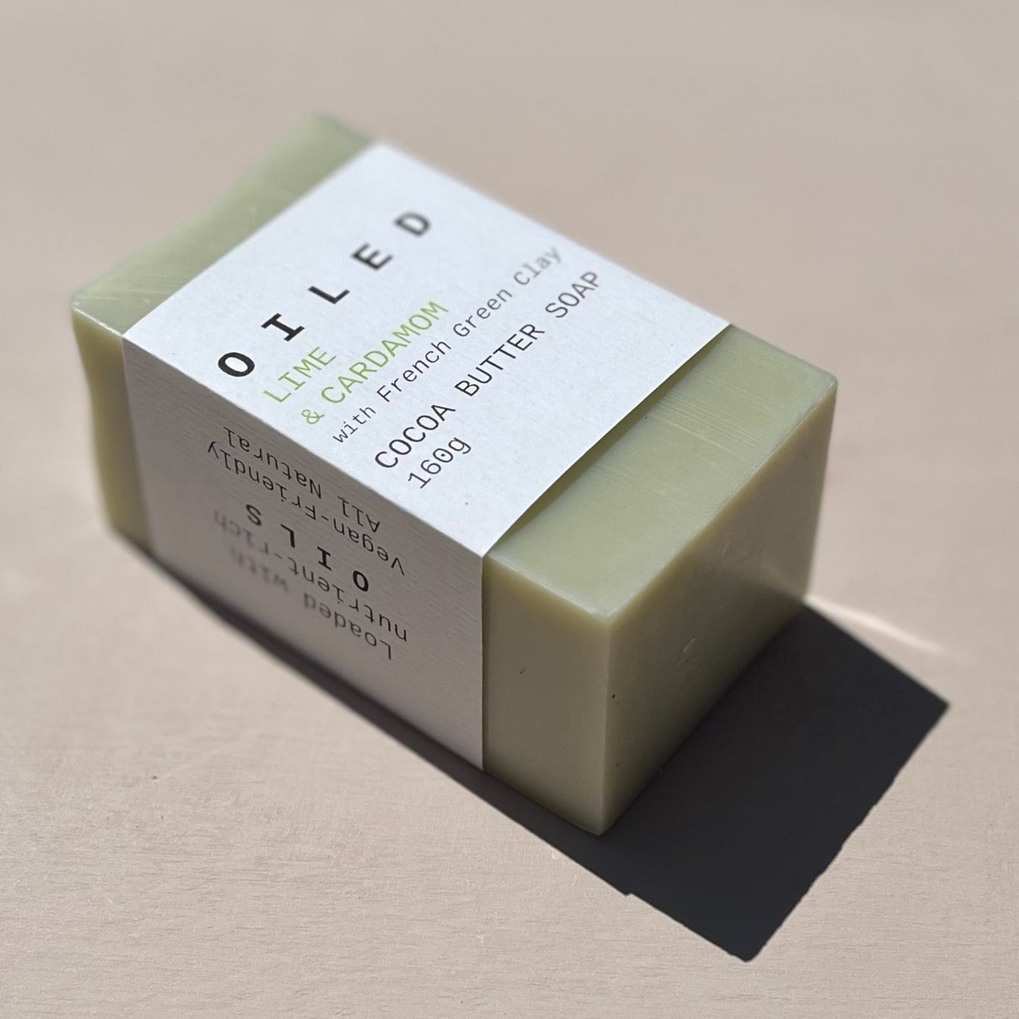 Bar of lime soap with a label on a light pink background