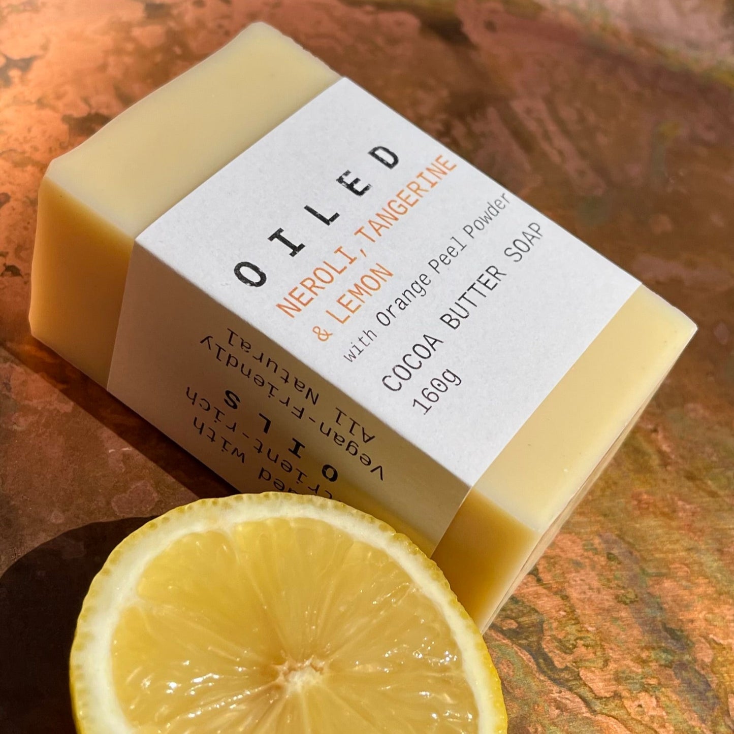 Bar of soap with a label and a lemon slice on a textured surface
