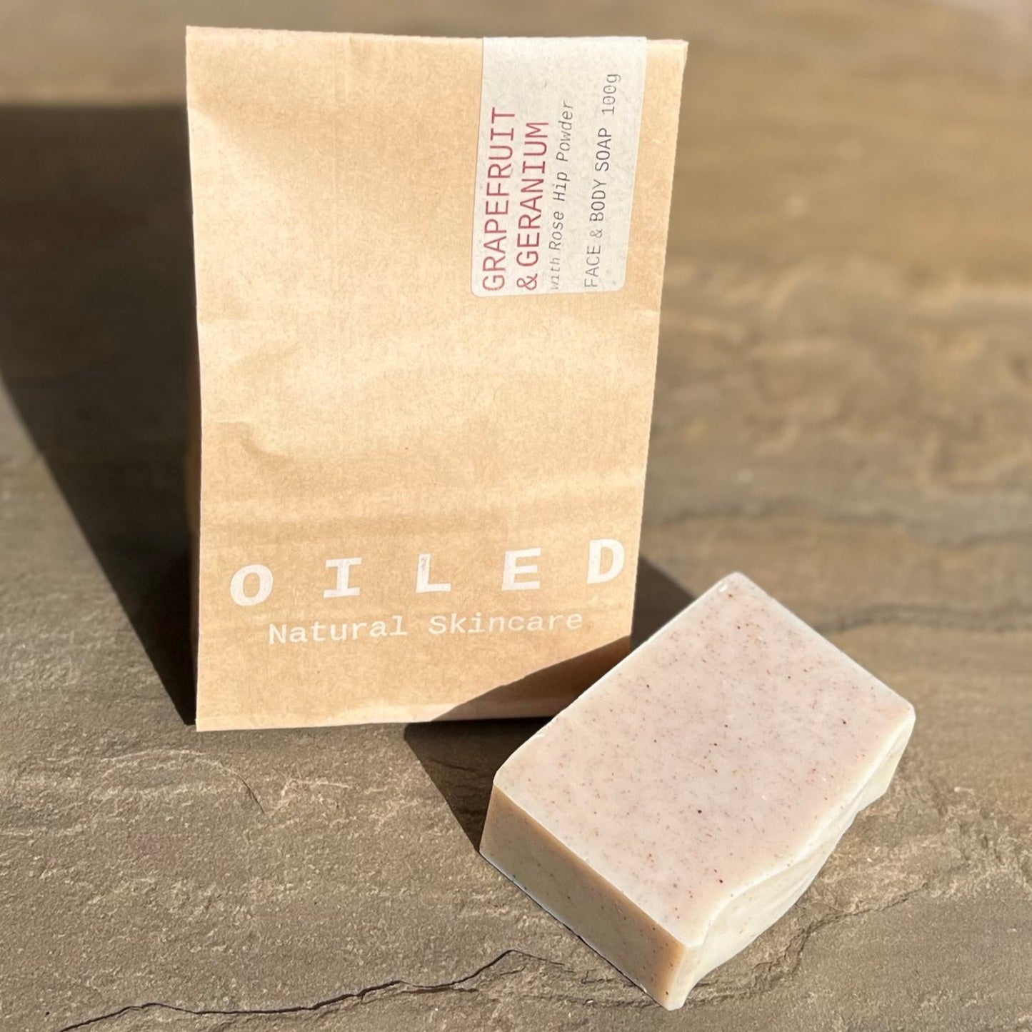 Bar of soap next to a brown paper bag printed with 'Oiled Natural Skincare'.