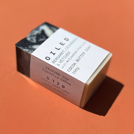 Bar of black and white swirly soap with 'Oiled' packaging on an orange background