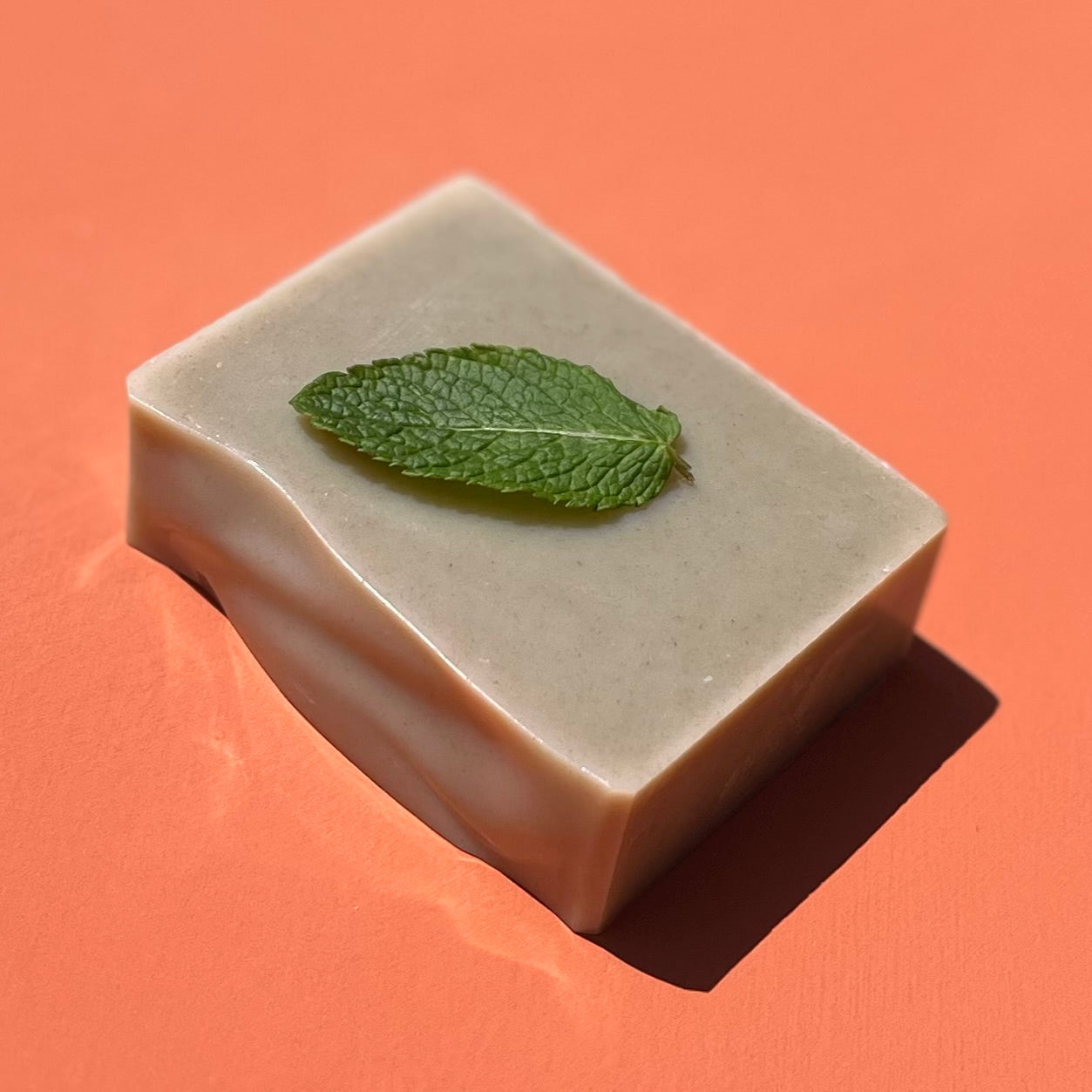 Bar of soap with a mint leaf on an orange background