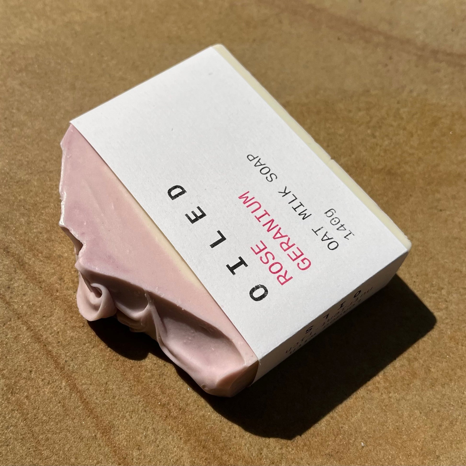 Bar of  oat milk soap with a white label on a brown background