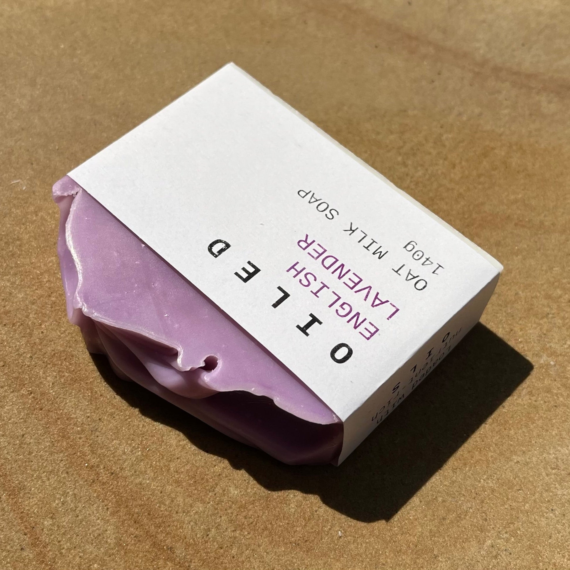 Lavender soap bar with a white label on a sa backgrounddstone