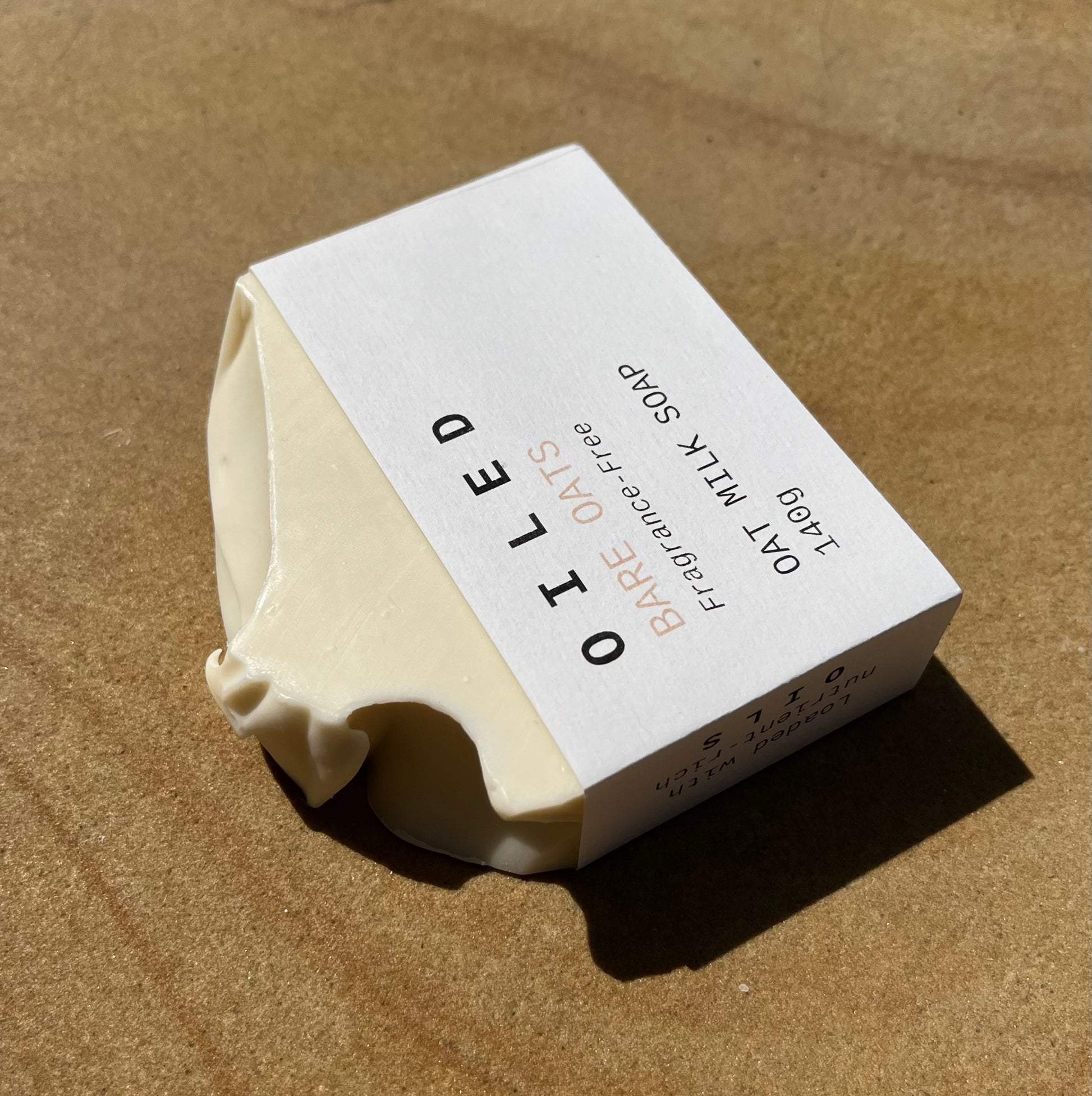 Oiled Bare Oats Soap with a white label on a sandstone background
