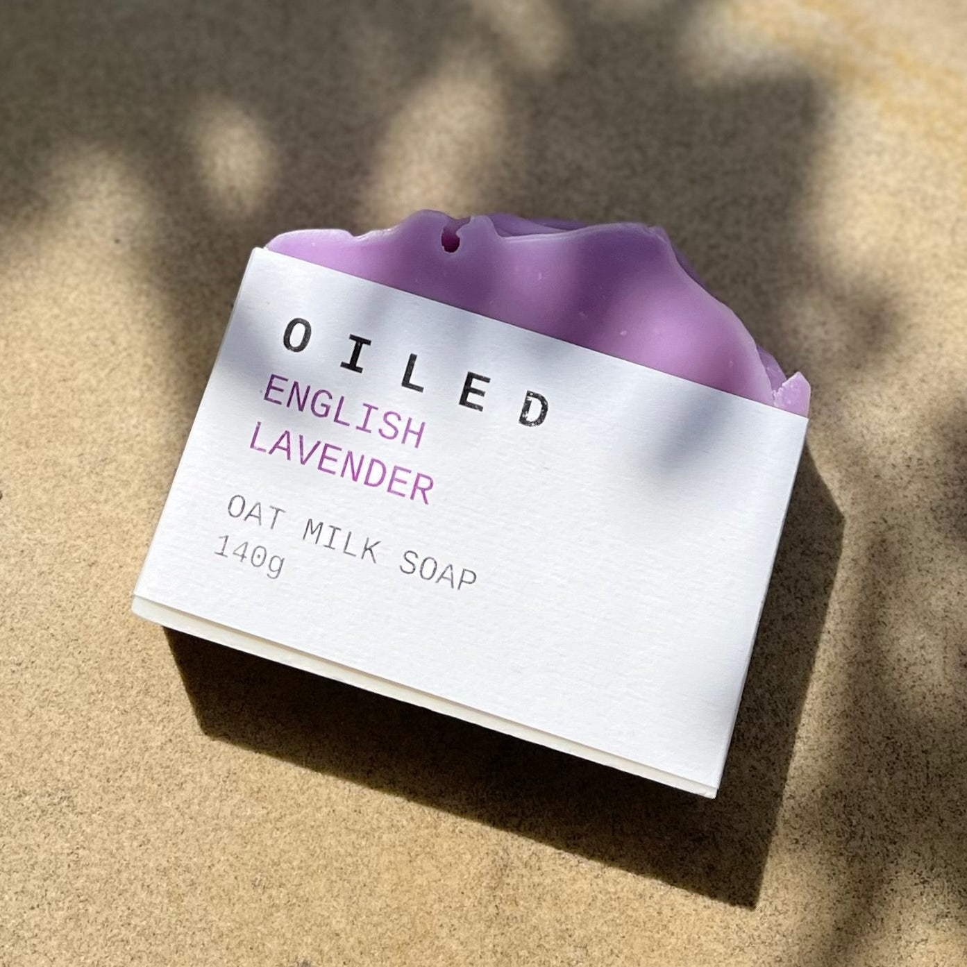 Oiled English Lavender oat milk soap on a sandy surface