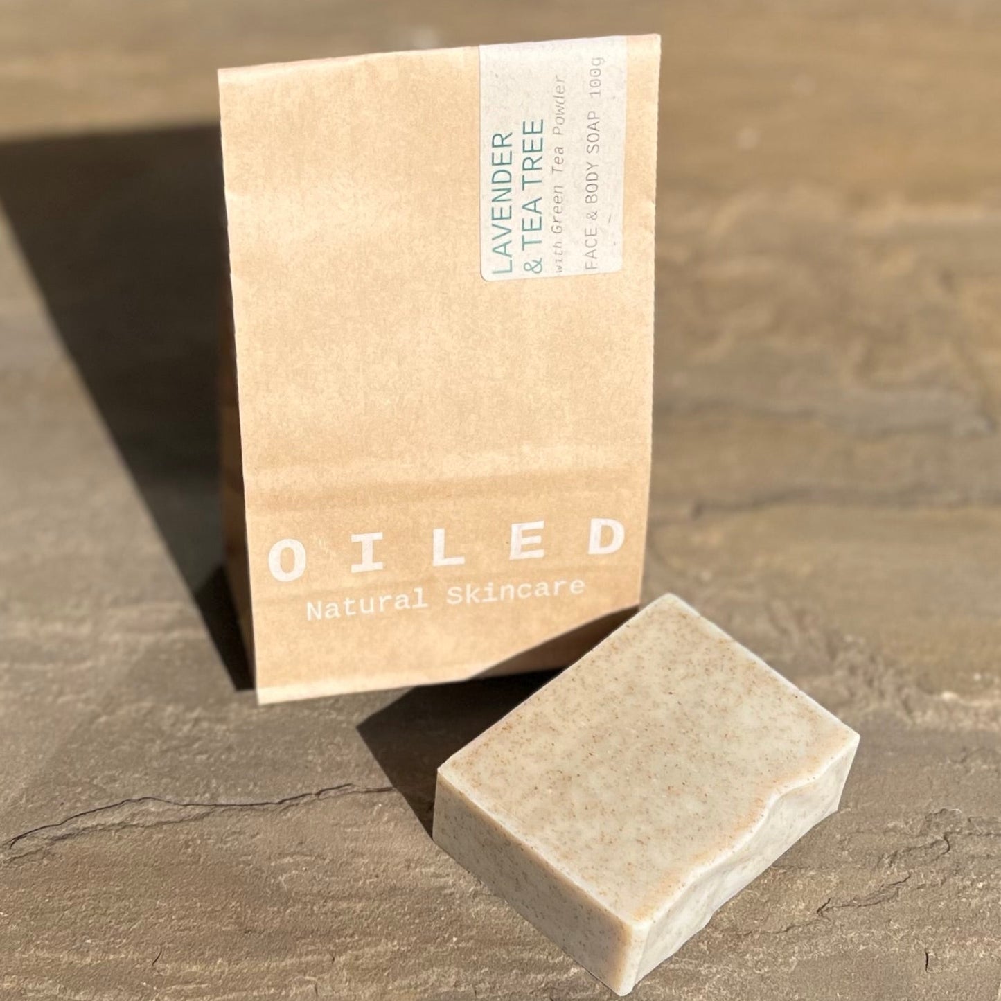 Bar of soap and Oiled Natural Skincare packaging on a stone surface