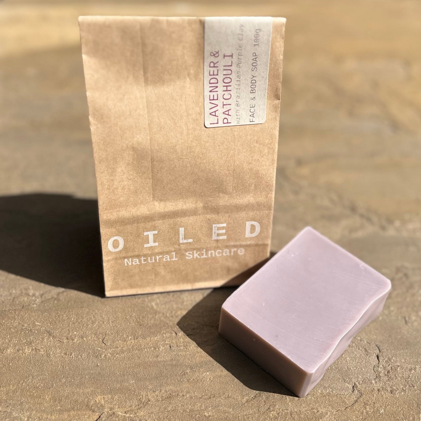 Purple bar of soap next to brown paper bag packaging