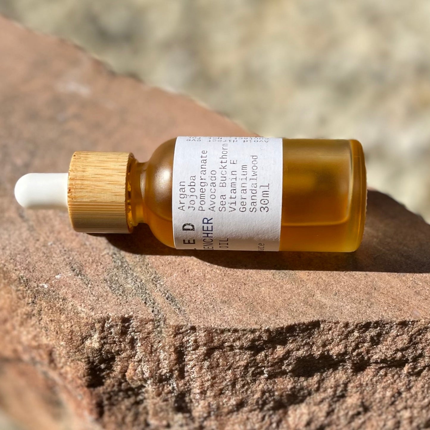 Bottle of skincare oil with dropper on a stone surface