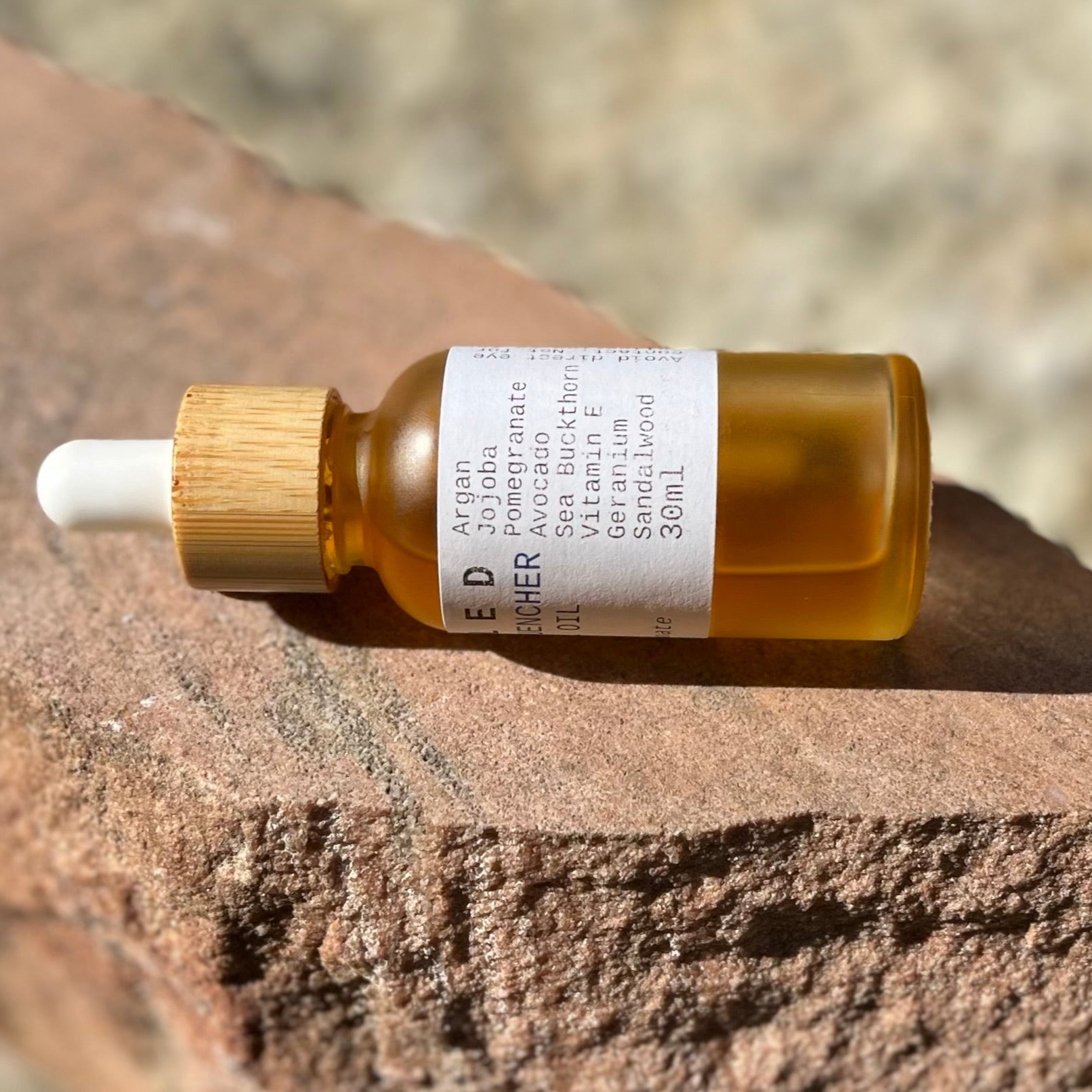 Bottle of skincare oil with dropper on a stone surface
