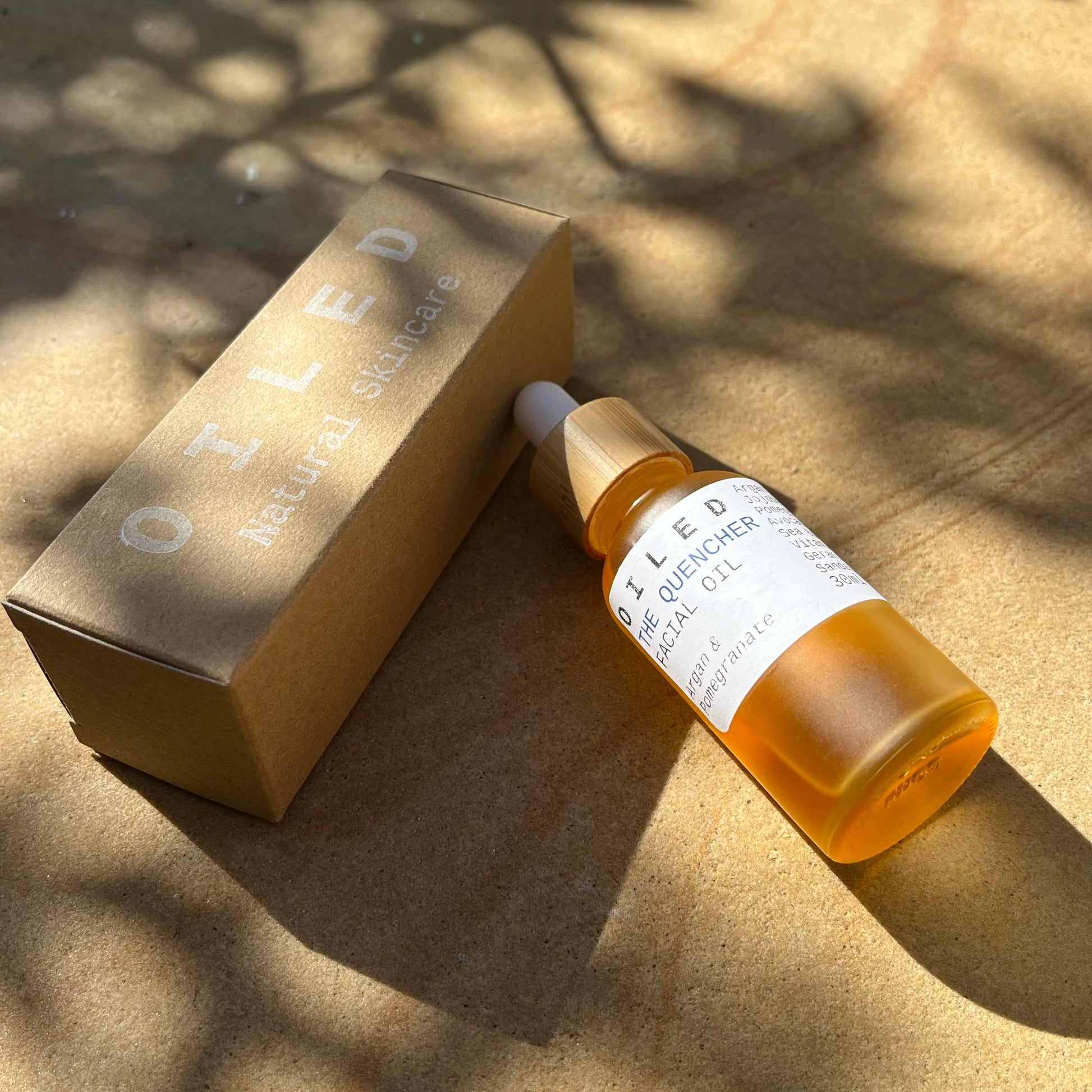 Oiled skincare bottle and packaging on a textured surface