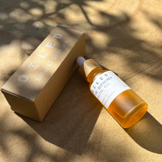 Oiled skincare bottle and packaging on a textured surface