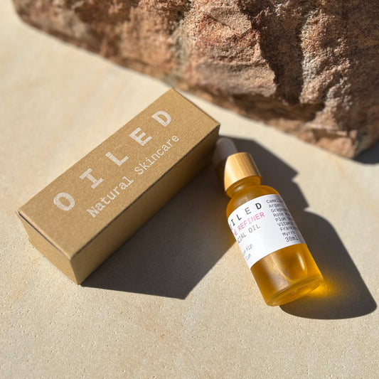 Oiled skincare product bottle and box on a stone surface