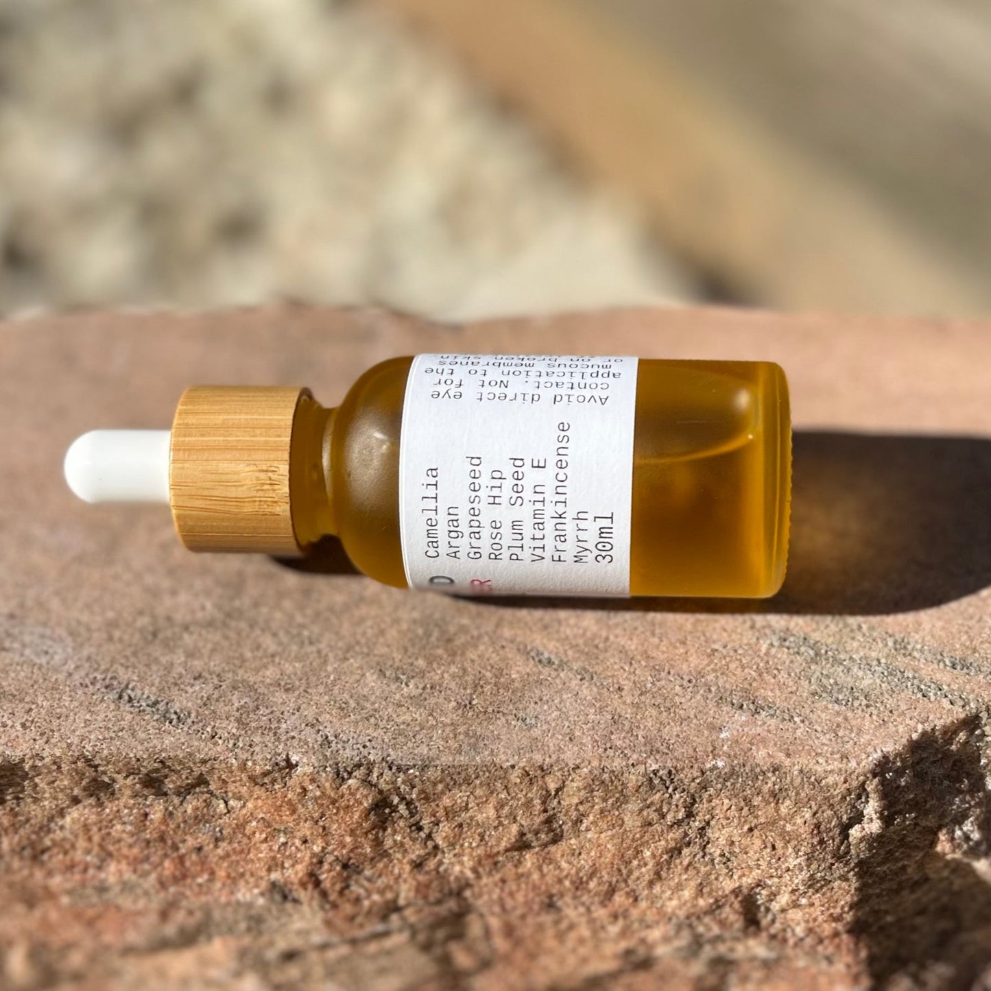 Small glass bottle with wooden cap and dropper on a stone surface