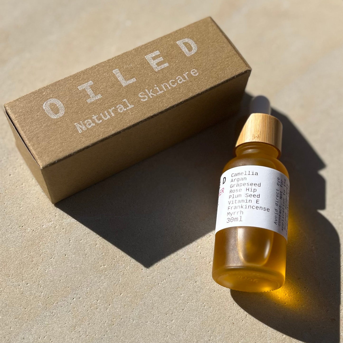 Oiled natural skincare bottle and box on a neutral background