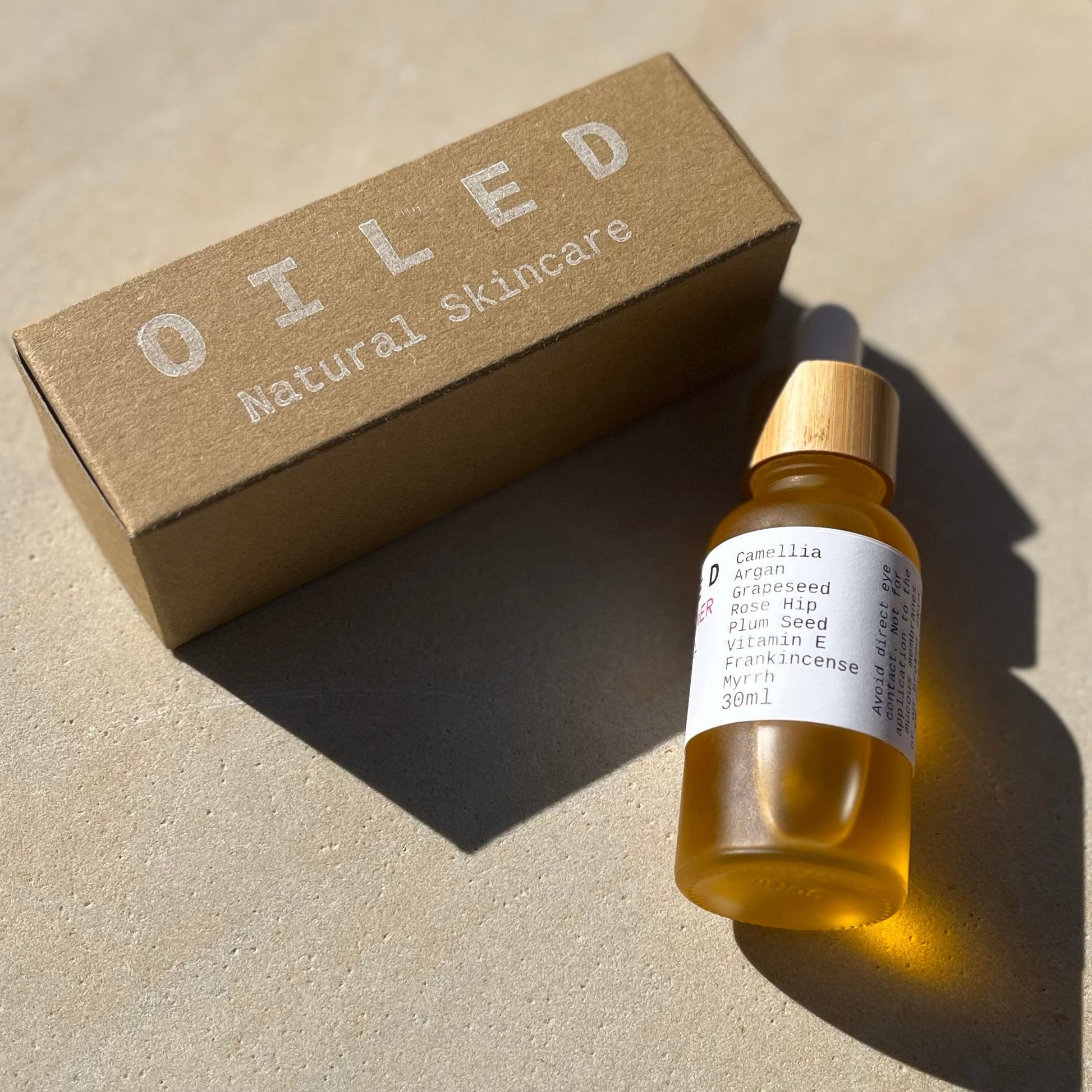Oiled natural skincare bottle and box on a neutral background