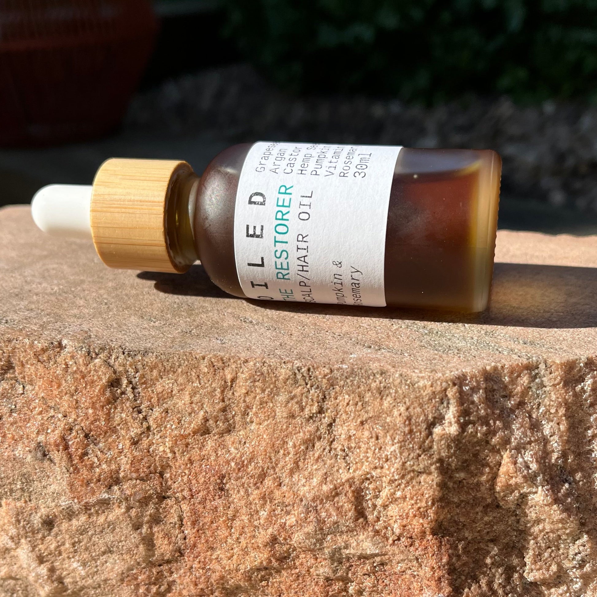 Bottle of OILED Restorer Oil on a stone surface with a blurred background