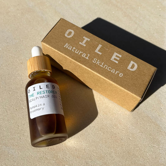 Oiled natural skincare bottle and box on a beige surface